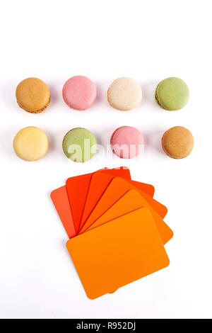 Colorati macarons francese con i campioni di colore in rosso aranciati. Vista da sopra con lo spazio di copia Foto Stock