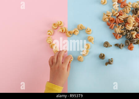 La mano della bambina messa a forma di cuore da gusci di pasta Foto Stock