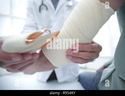 Ortopedico applicando un bendaggio sulla mano del paziente in clinica Foto Stock