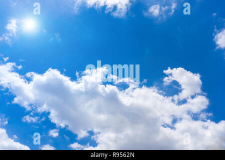 Bianchi e soffici nuvole e sole sul davanti del cielo blu. Foto Stock