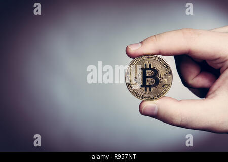 Bitcoin cryptocurrency moneta in oro in mano d'uomo Foto Stock