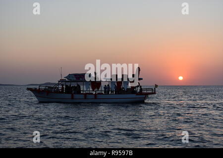 I turisti in una gita in barca nella baia di San Antonio a guardare il tramonto, San Antonio, Ibiza, Spagna Foto Stock