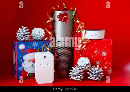 Amazon Echo Echo Dot e Smart Plug con decorazioni di Natale su uno sfondo rosso Foto Stock