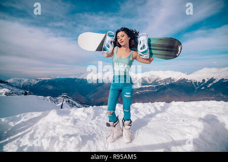 Ragazza snowboarder si erge con lo snowboard sulle montagne top Foto Stock