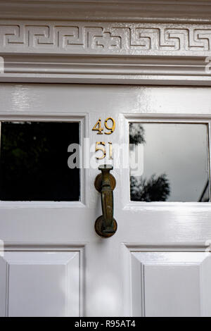 Il numero civico 49 & 51 su un dipinto di bianco di telaio porta a Hertfordshire, con una pesante porta di ottone respingente Foto Stock