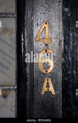 Il numero civico 46A in ottone su un nero porta in legno Foto Stock