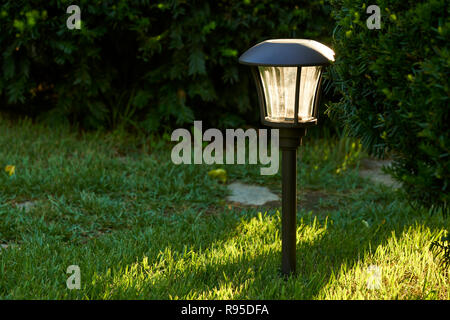 La luce del sole e le luci solari per esterni di percorso in un giardino Foto Stock