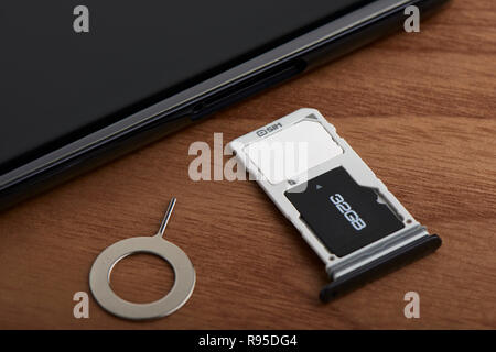 Scheda SIM e la scheda microSD vassoio con lo strumento di rimozione sul lato dello smartphone Foto Stock