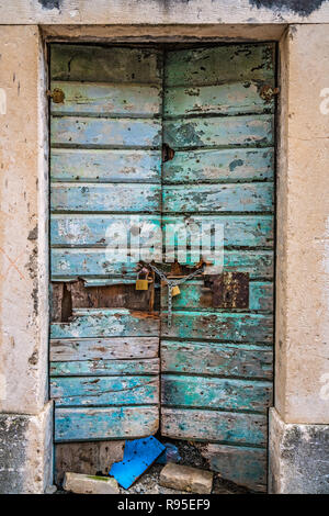 Bloccato con lucchetti e catene verde vecchio danneggiato porte in legno in uno degli edifici di Kotor, Montenegro Foto Stock