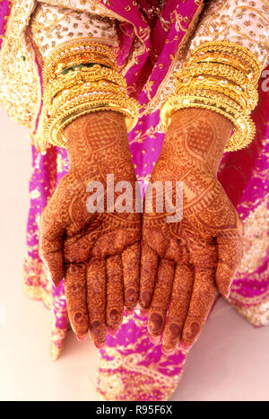 Mani di sposa con mehndi e bangles d'oro Foto Stock