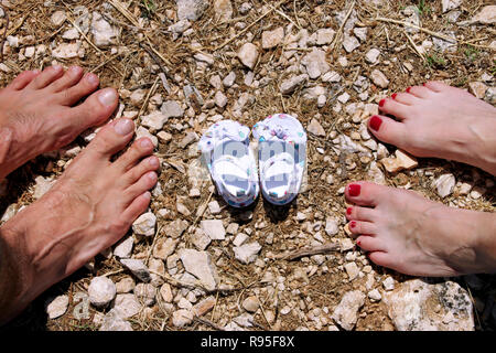 Felice famiglia giovani in attesa di baby, di amore e di felicità. Futura Mamma e papà piedi con il piccolo bambino scarpe, closeup. Nascita attesa concetto. Foto Stock