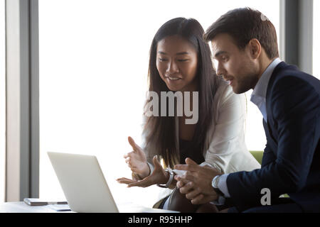 Attraente asiatiche positivo lavoro femminile con uomo caucasico usin Foto Stock
