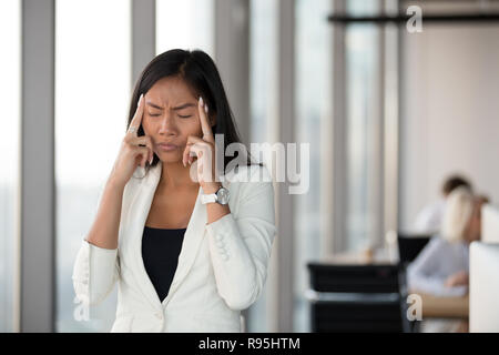 Asian attraente giovane donna touch templi massaggiante si sente herse Foto Stock