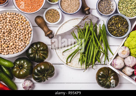 Cibo vegan cottura Ingredienti,bianco sullo sfondo di legno, vista dall'alto, con diversi ortaggi e legumi Foto Stock