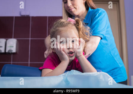 Fisioterapia con bambino con paralisi cerebrale. Una bambina getta sul lettino Foto Stock