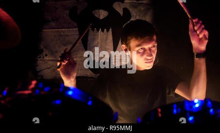 Concerto rock. Un uomo suonando la batteria sul palco. Il batterista holding bacchette. Foto Stock
