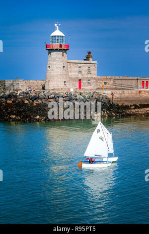 Un bianco di crociera in barca a vela in prossimità di un faro su acqua blu, Malahide, Dublino, Irlanda Foto Stock