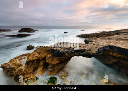 Seascape in Cascais Portogallo. Il ponte di pietra scolpita dalle maree. Il paesaggio costiero vicino a Lisbona. Esposizione a lungo su un giorno di tempesta. Foto Stock