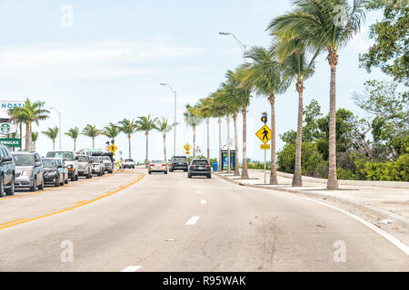 Key West, Stati Uniti d'America - 1 Maggio 2018: Righe, fila di molte palme sul boulevard con molte vetture, cartelli stradali in Florida keys urban isola sulla Overseas Highway Foto Stock