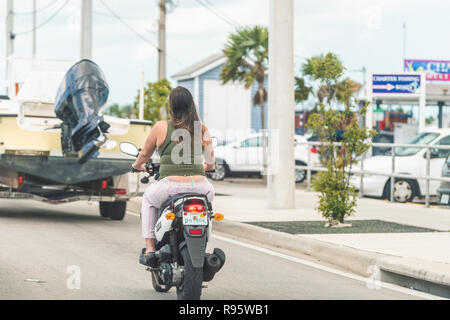 Key West, Stati Uniti d'America - 1 Maggio 2018: Overseas Highway Road, US1, traffico di automobili in piedi, arrestato, indietro alle spalle della donna seduta, equitazione motocicletta, scooter Foto Stock