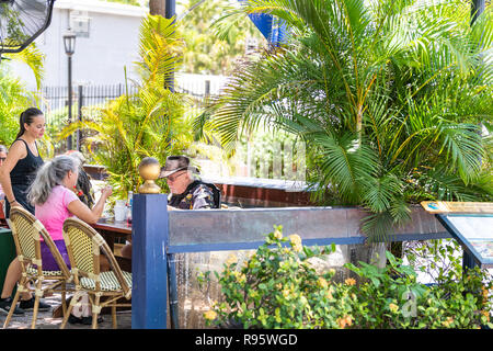 Key West, Stati Uniti d'America - 1 Maggio 2018: Cameriere, persone Coppia senior, seduti a un tavolo con le sedie, fuori all'aperto in blu Macaw Island mangia, bar, ristorante, ord Foto Stock