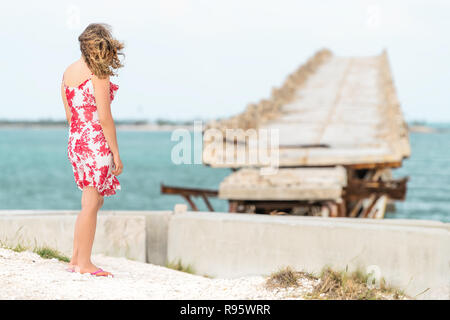 Giovane donna in piedi di fronte a vecchi Seven Mile Bridge, Cavalieri Key-Pigeon Key-Moser canale Channel-Pacet, vento windy, horizon seascape in Bahia Hon Foto Stock