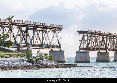 Vecchio arrugginito, ruggine, rusty derelitti Bahia Honda rail road in stato parco con vista sulla riva, costa, Palm tree, nubi nuvoloso cielo blu al tramonto, crepuscolo, h Foto Stock