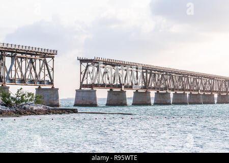 Vecchio arrugginito, ruggine, rusty derelitti Bahia Honda rail road bridge in stato parco con vista sulla riva, costa, albero, nuvole, nuvoloso cielo blu al tramonto, crepuscolo, Foto Stock