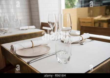 Un tavolo da pranzo è visto essendo reso pronto per i clienti. La tabella è vuota ma la bella di piastre in ceramica e bicchieri sembra molto sofisticati. Foto Stock