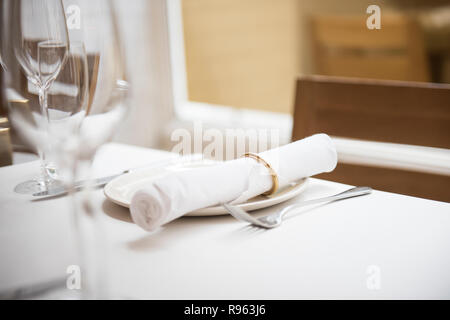 Un tavolo da pranzo è visto essendo reso pronto per i clienti. La tabella è vuota ma la bella di piastre in ceramica e bicchieri sembra molto sofisticati. Foto Stock