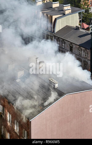 Fumo denso proveniente dal tetto di un edificio in fiamme. Foto Stock