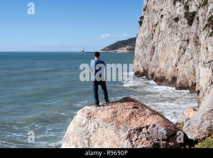 Giovane uomo in piedi sulle rocce in Spagna Garaff affacciata sul Mediterraneo Foto Stock