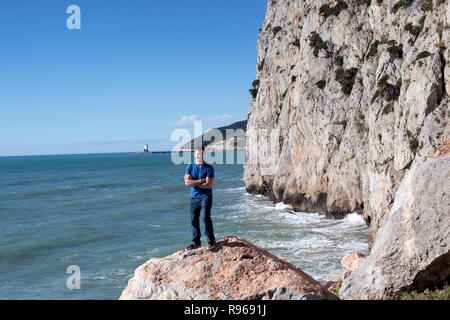 Giovane uomo in piedi sulle rocce in Spagna Garaff affacciata sul Mediterraneo Foto Stock