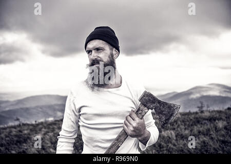 Lumberjack. uomo barbuto, barba lunga e brutali caucasian hipster con baffi contiene ax con gravi faccia sulla cima della montagna . barba. barba lunga ragazzo con capelli elegante ottenere barbe haircut Foto Stock