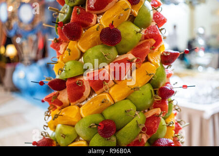 Frutti tropicali tagliare thtower di trito di frutta tropicale e fragole al banchetto. antipasto al banchetto. dessert alla frutta Frutta toweran Tower con ananas Foto Stock