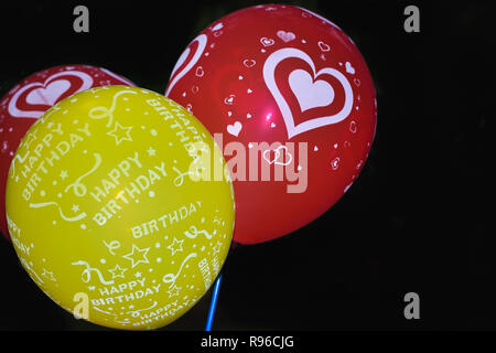 Set di battenti di palloncini di rosa rosso verde colore. Flying compleanno palloncino elio. Isolato su sfondo nero. Celebrazioni di partito decorazioni concetto. Foto Stock