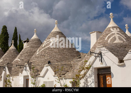 Imbiancati tradizionali trulli case con tetti conici e simboli in Alberobello Puglia, Italia meridionale Foto Stock