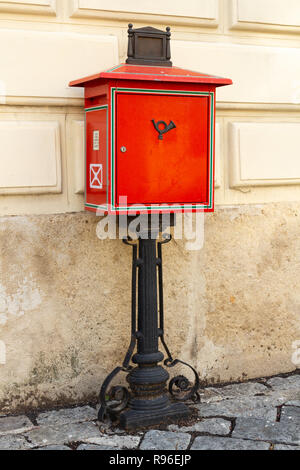 Tradizionale cassetta postale rosso su nero ferro battuto stand nella piazza principale di Sopron, Ungheria. L'immagine verticale. Foto Stock