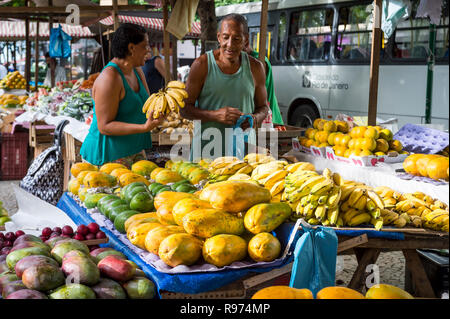 RIO DE JANEIRO - febbraio, 2017: un fornitore condivide un ridere con un cliente al suo in stallo il settimanale mercato degli agricoltori la vendita di frutta tropicale e la veg. Foto Stock