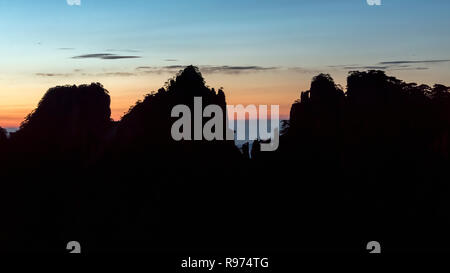 Sunrise e Huangshan pine-sormontato cliffs, Huangshan Parco Nazionale di Anhui, Cina Foto Stock