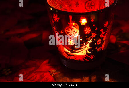 Il Natale porta candele acceso con una vacanza bagliore rosso, raffigura scene di inverno e di neve dalla fiamma all'interno. Foto Stock