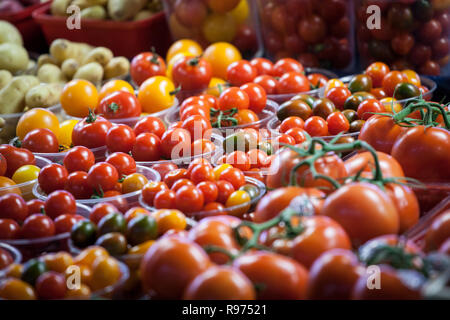 Pomodori ciliegia di diverse dimensioni dans colori, rosso giallo e verde per la vendita su un mercato canadese di Montreal, visualizzati in cestelli di plastica e punn Foto Stock