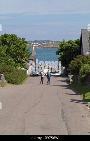 Guardando giù per la collina dal monastero, passeggeri a piedi, partenza da Iona, per il traghetto per Fionnphort, Mull, all'orizzonte. Per il Quayside, Porto Ronain.​​ Foto Stock