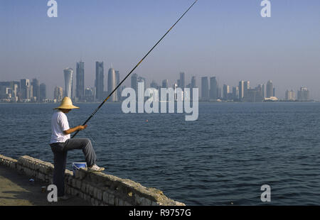 13.09.2010, Doha, Qatar - un uomo è la pesca in mare lungo la Corniche Promenade affacciata sullo skyline della città del Central Business District. Foto Stock