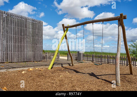 Swing in legno su un parco giochi per bambini in un giorno di estate Foto Stock