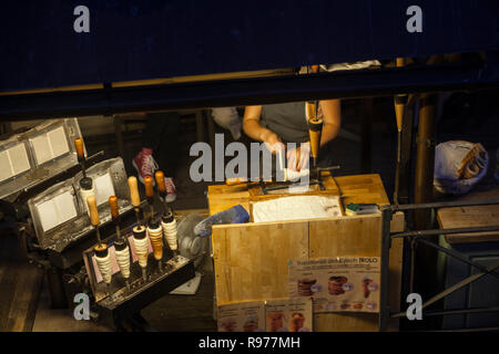 Praga, Repubblica Ceca - 14 Luglio 2018: stand al Ponte Charles in cui una donna rende trdelnik, il quale è costituito da un laminato in pasta che viene avvolto aro Foto Stock