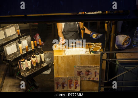 Praga, Repubblica Ceca - 14 Luglio 2018: stand al Ponte Charles in cui una donna rende trdelnik, il quale è costituito da un laminato in pasta che viene avvolto aro Foto Stock