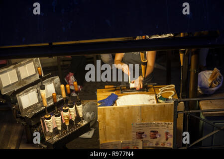 Praga, Repubblica Ceca - 14 Luglio 2018: stand al Ponte Charles in cui una donna rende trdelnik, il quale è costituito da un laminato in pasta che viene avvolto aro Foto Stock