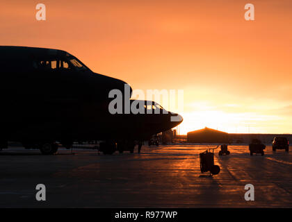 Il sole sorge alle spalle di una B-52H Stratofortress a Minot Air Force Base in North Dakota, Dic 12, 2018. Avieri dal 5 Manutenzione aeromobili squadrone lavorare intorno all'orologio in tutte le condizioni meteorologiche, per fornire la potenza di combattimento on-demand. (U.S. Air Force foto di Senior Airman Alyssa M. Akers) Foto Stock