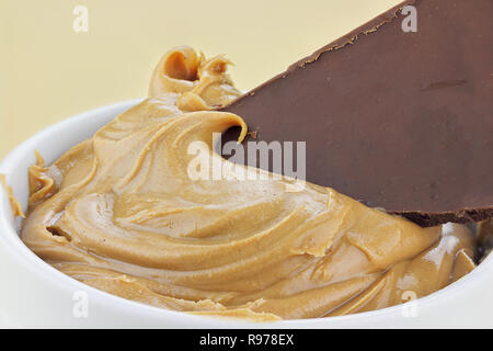 14964463 - Burro di arachidi con un pezzo di cioccolato candy bar immerso in essa. Foto Stock